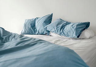 An unmaid bed with blankets, sheets, and pillows.